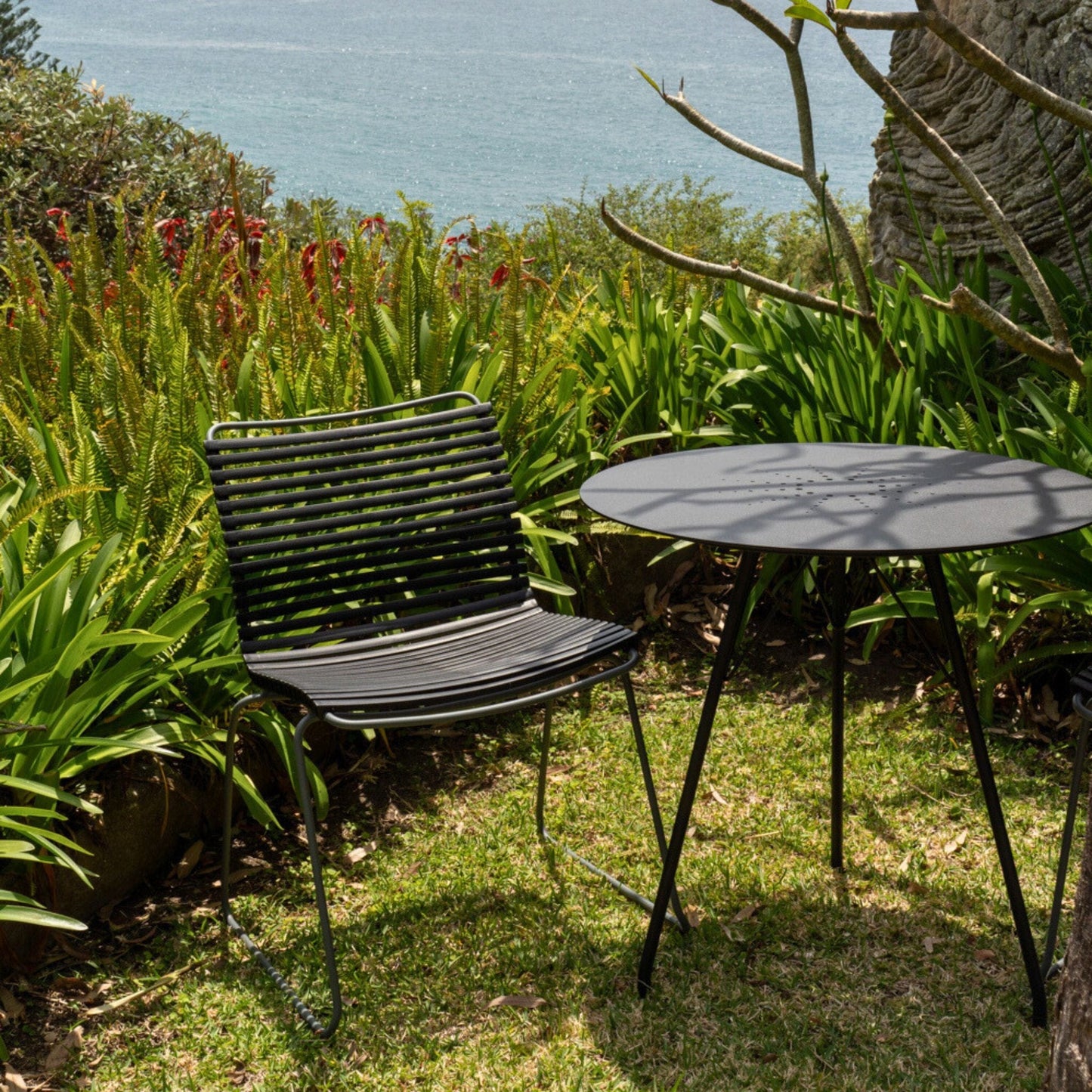 Black chair and table on a grassy lawn.