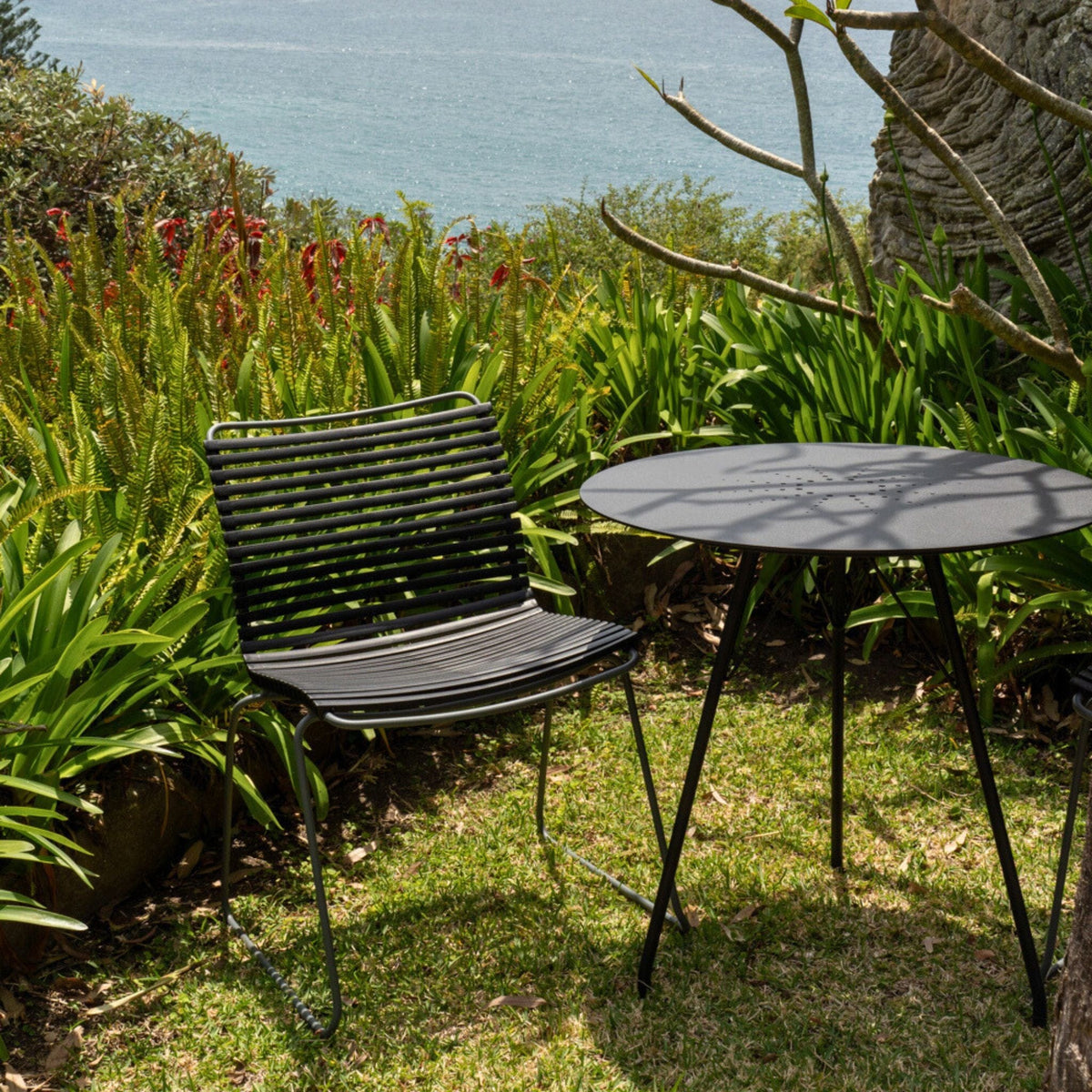 Black chair and table on a grassy lawn.