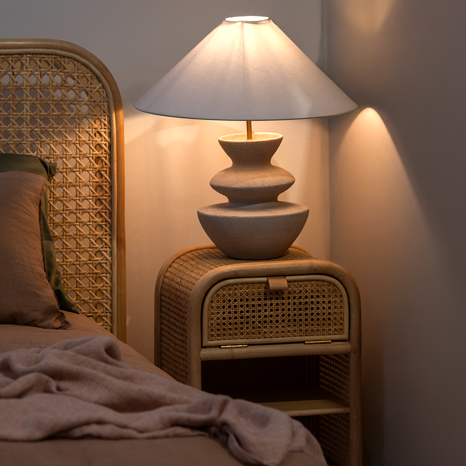 Wicker nightstand with lamp and bed in a dimly lit room