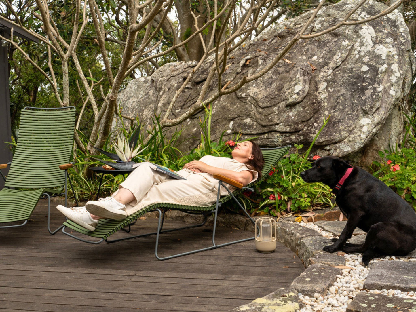 Woman relaxing in a chair with dog outdoors.