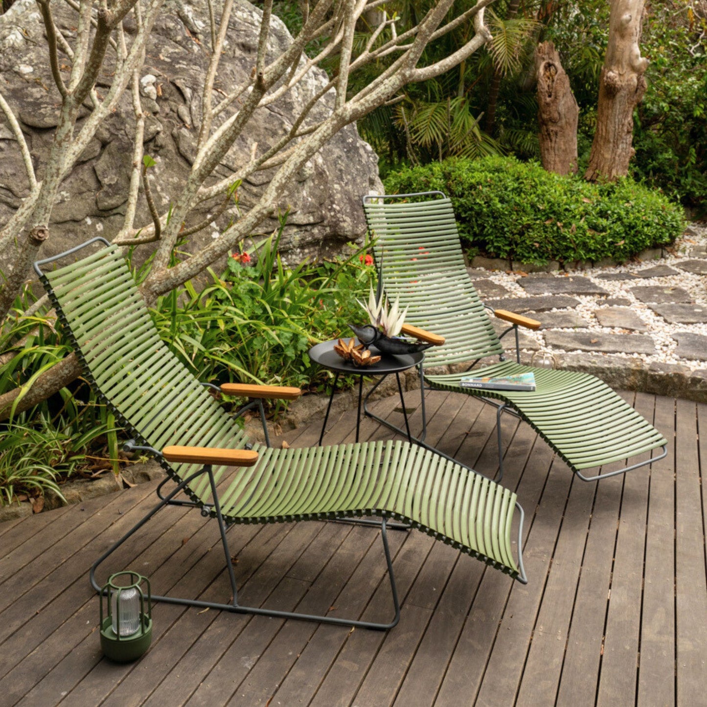 Two green chaise lounge chairs on a wooden deck.