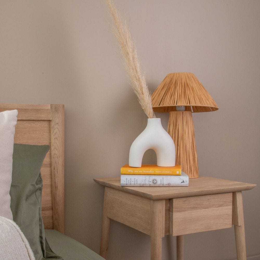 Bedside table with vase, lamp, and books