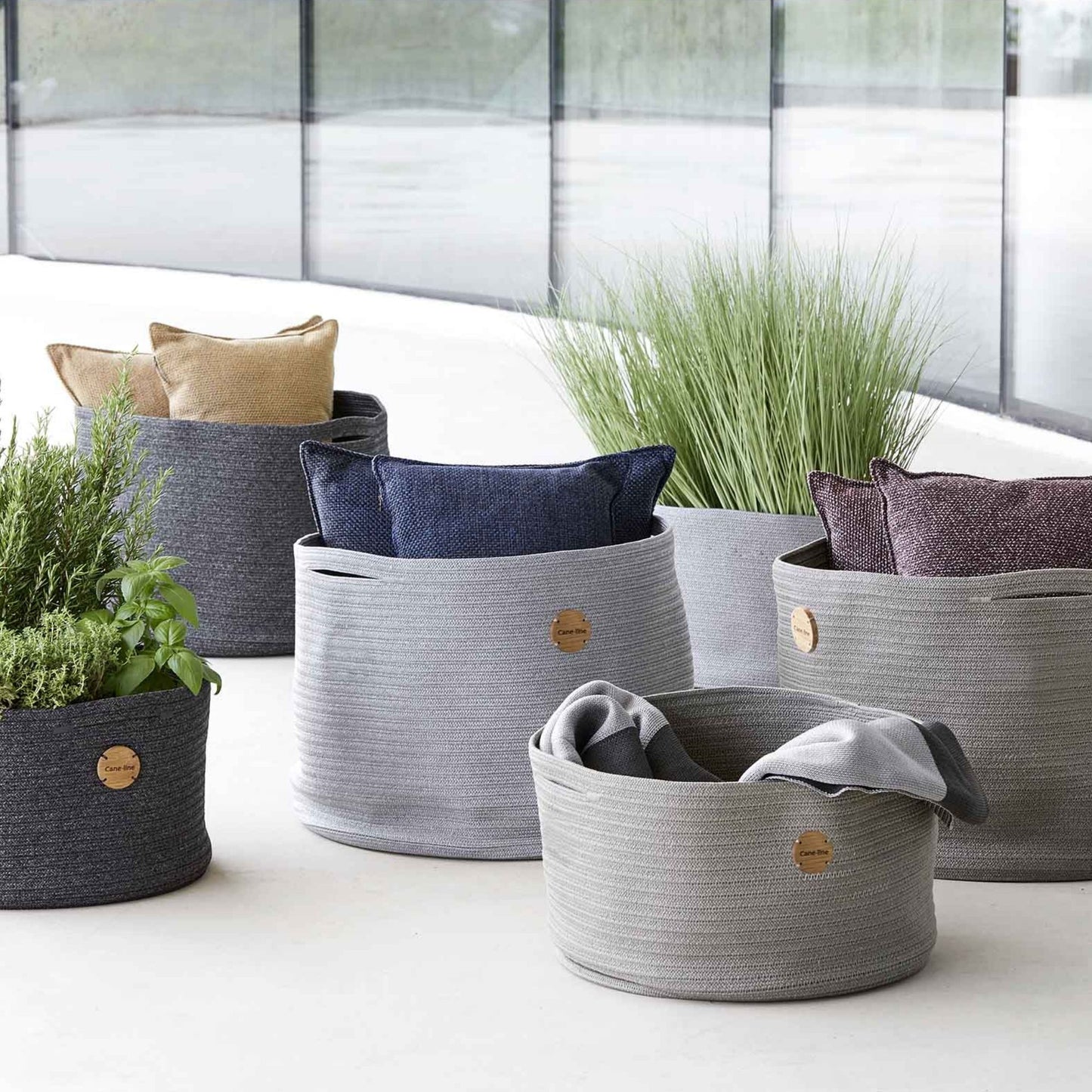 Grey rope baskets with pillows and plants.