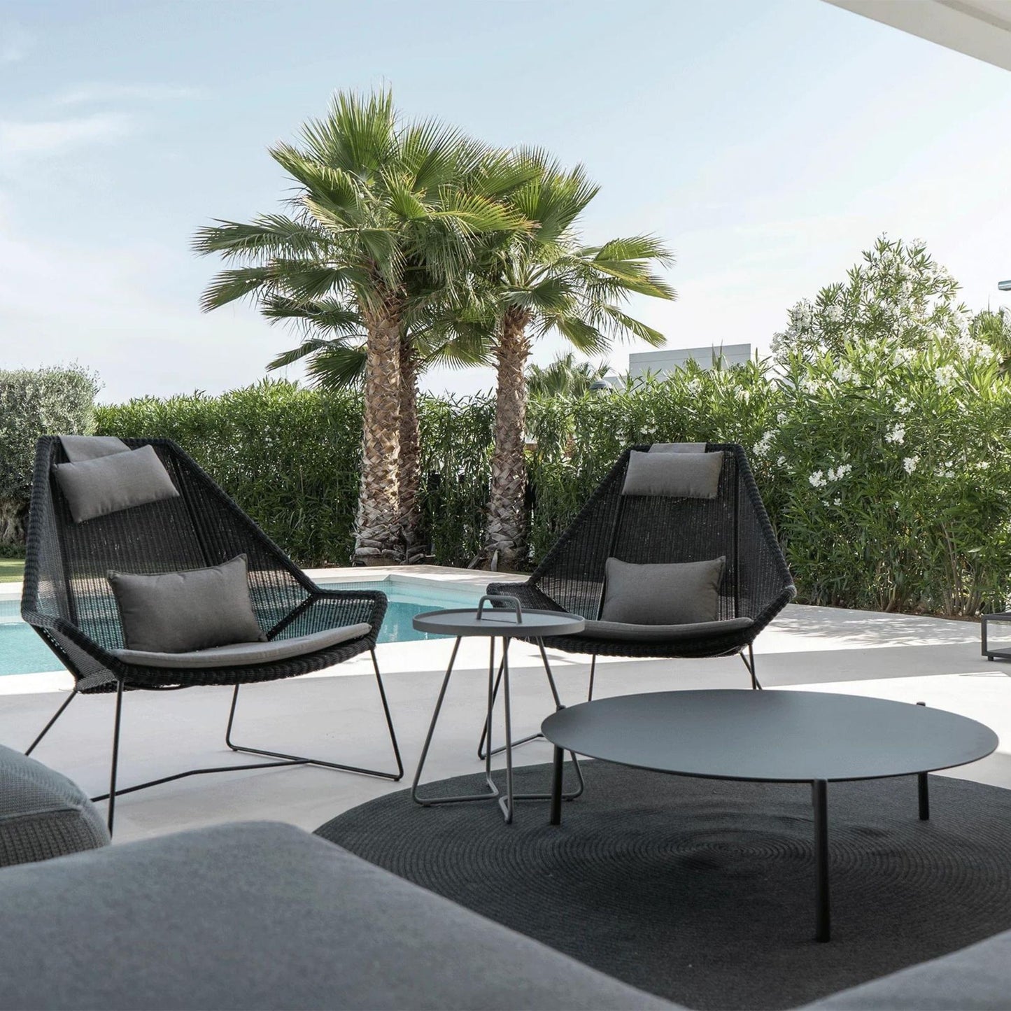 Modern patio chairs with coffee table and pool view.