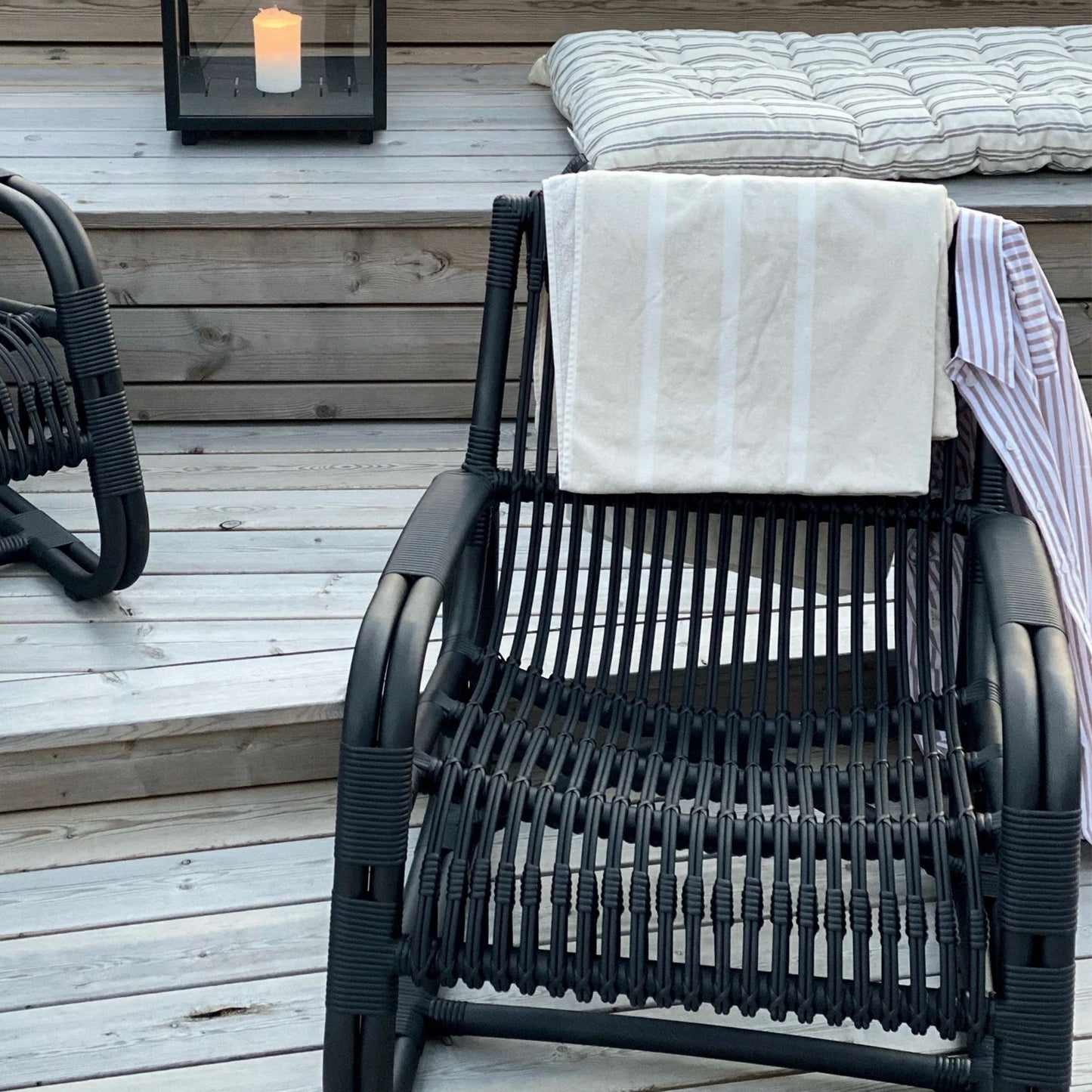 Black outdoor chair with towel and striped shirt on deck, 57402ALG_4