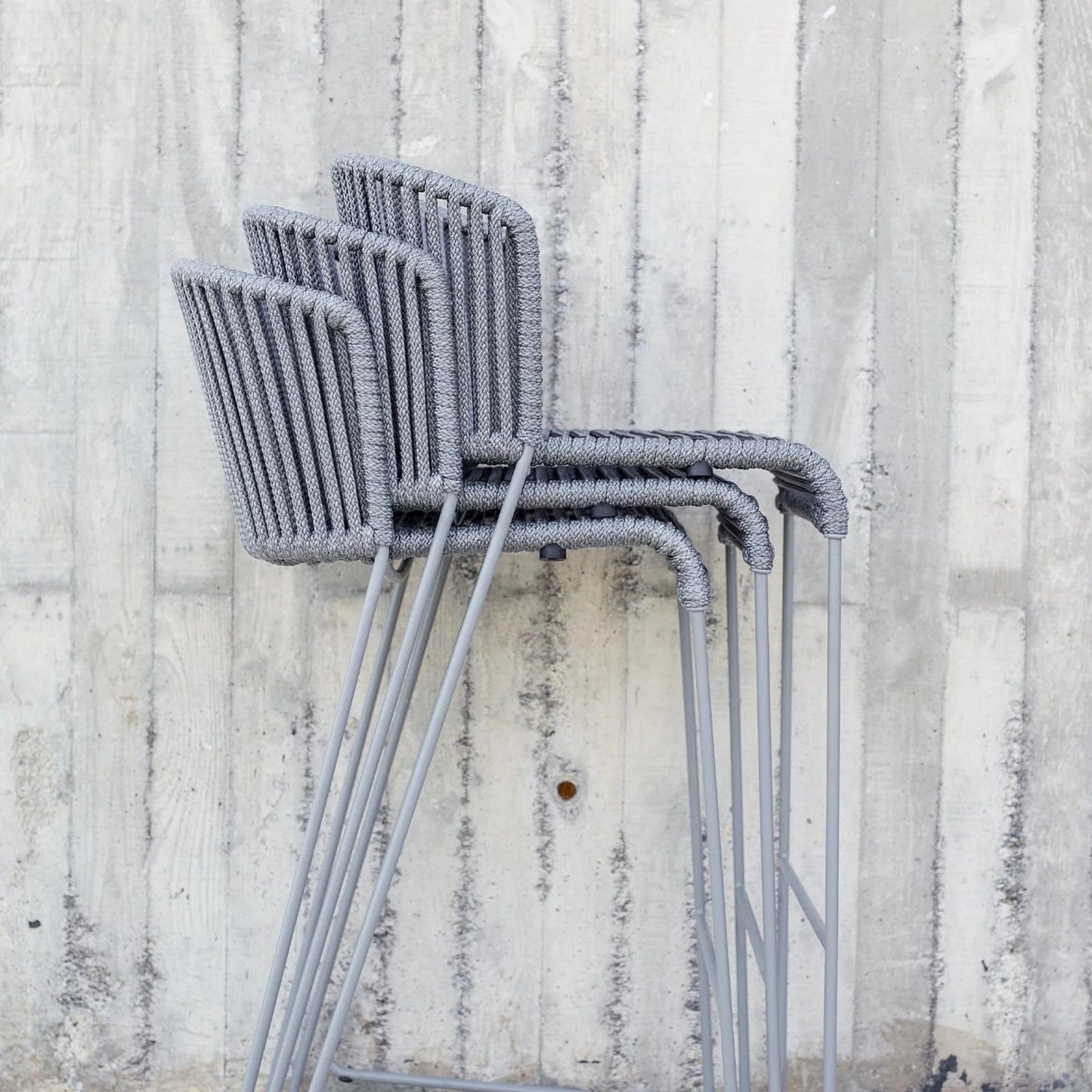 Stacked grey ROG chairs against concrete wall