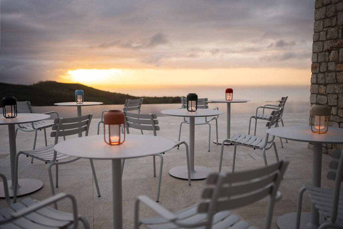 Outdoor dining set with muted white round tables and lanterns at sunset