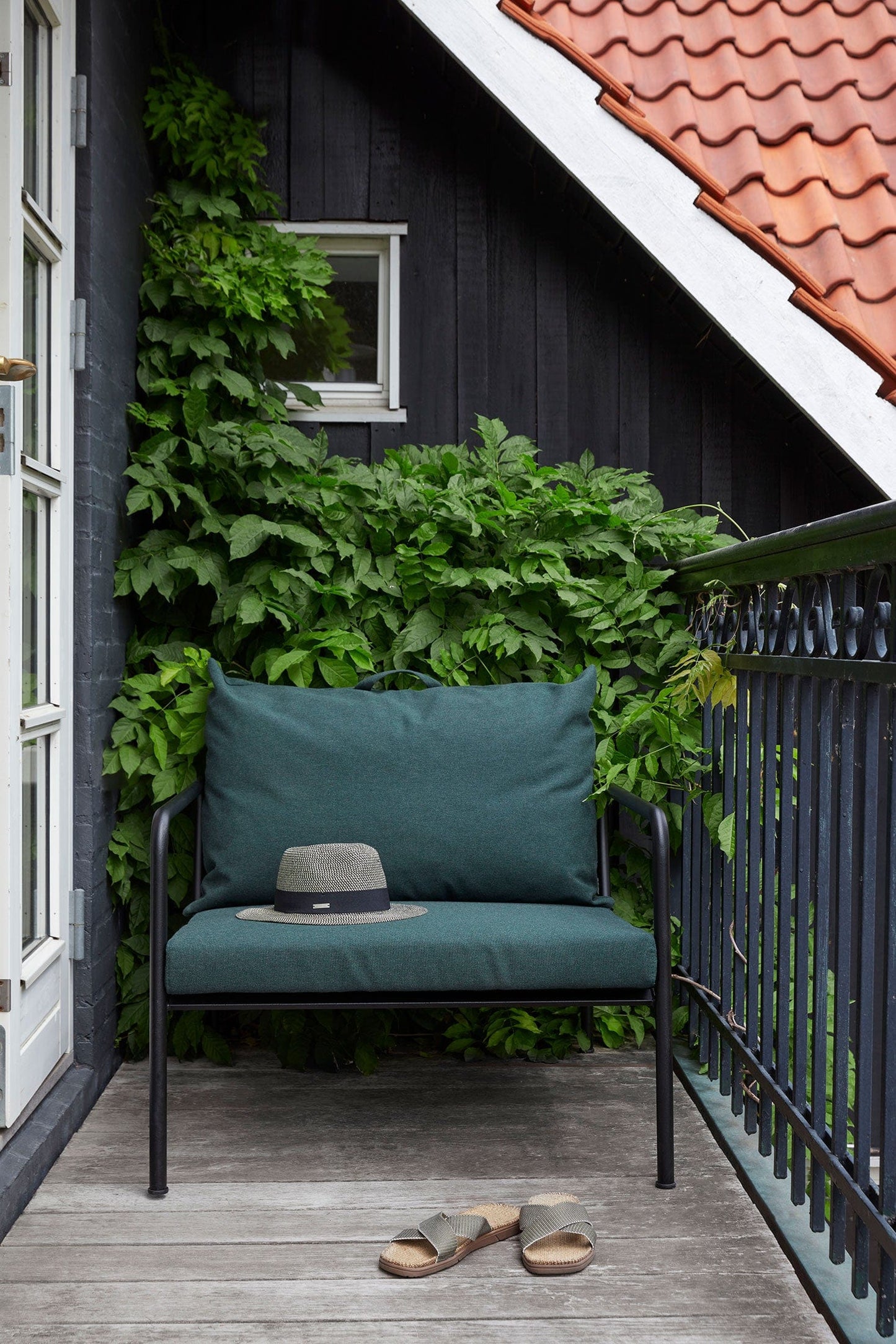 AVON alpine chair with cushion, hat, and sandals on a balcony.