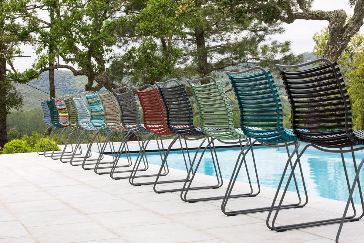 CLICK Dining chairs in a row, various colors, by pool.