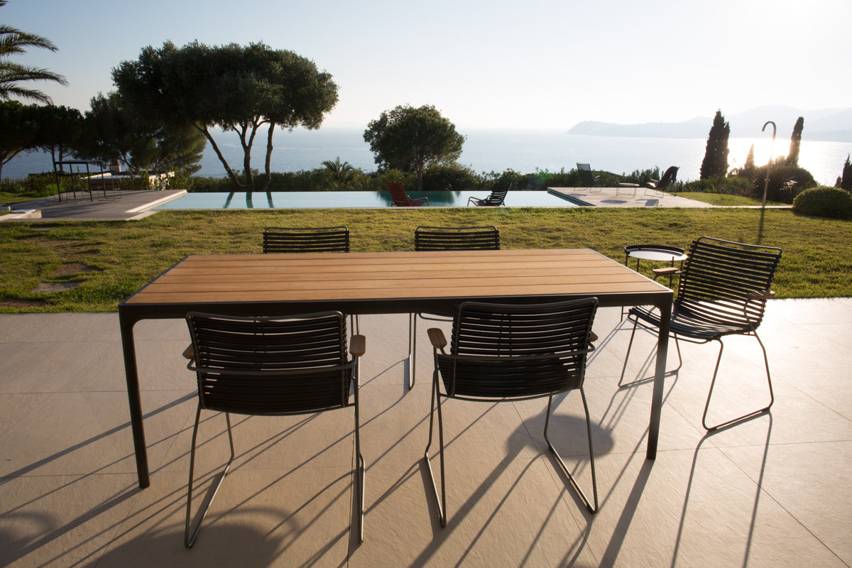 Black bamboo dining table set overlooking pool and ocean
