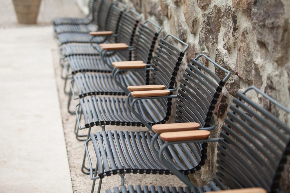Black HOUE dining chairs in a row by a stone wall