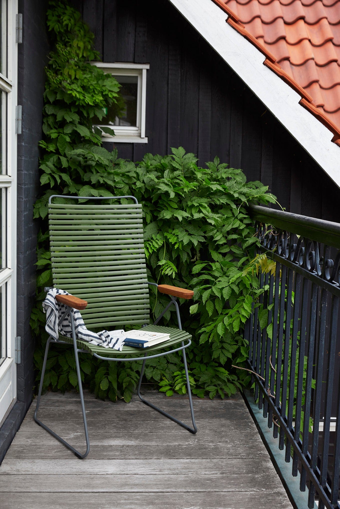 Olive green chair on balcony with foliage