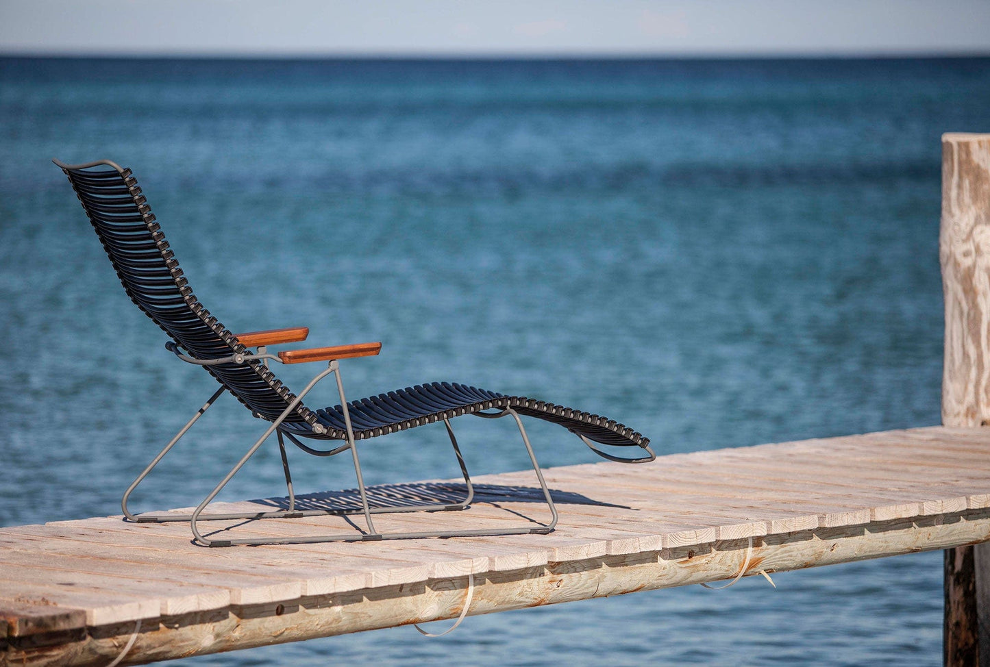 Black HOUE CLICK sunlounger on wooden dock overlooking the ocean