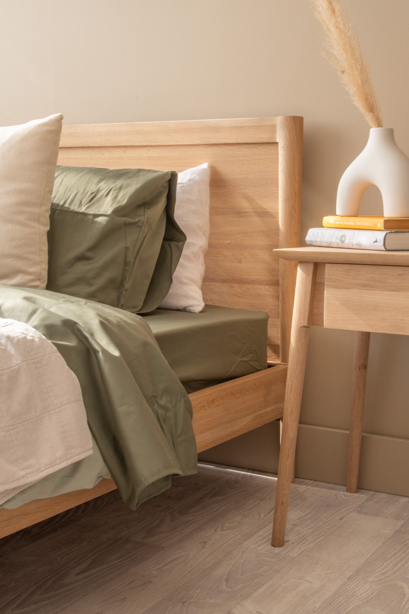 Olive green bedding on a wooden bed frame