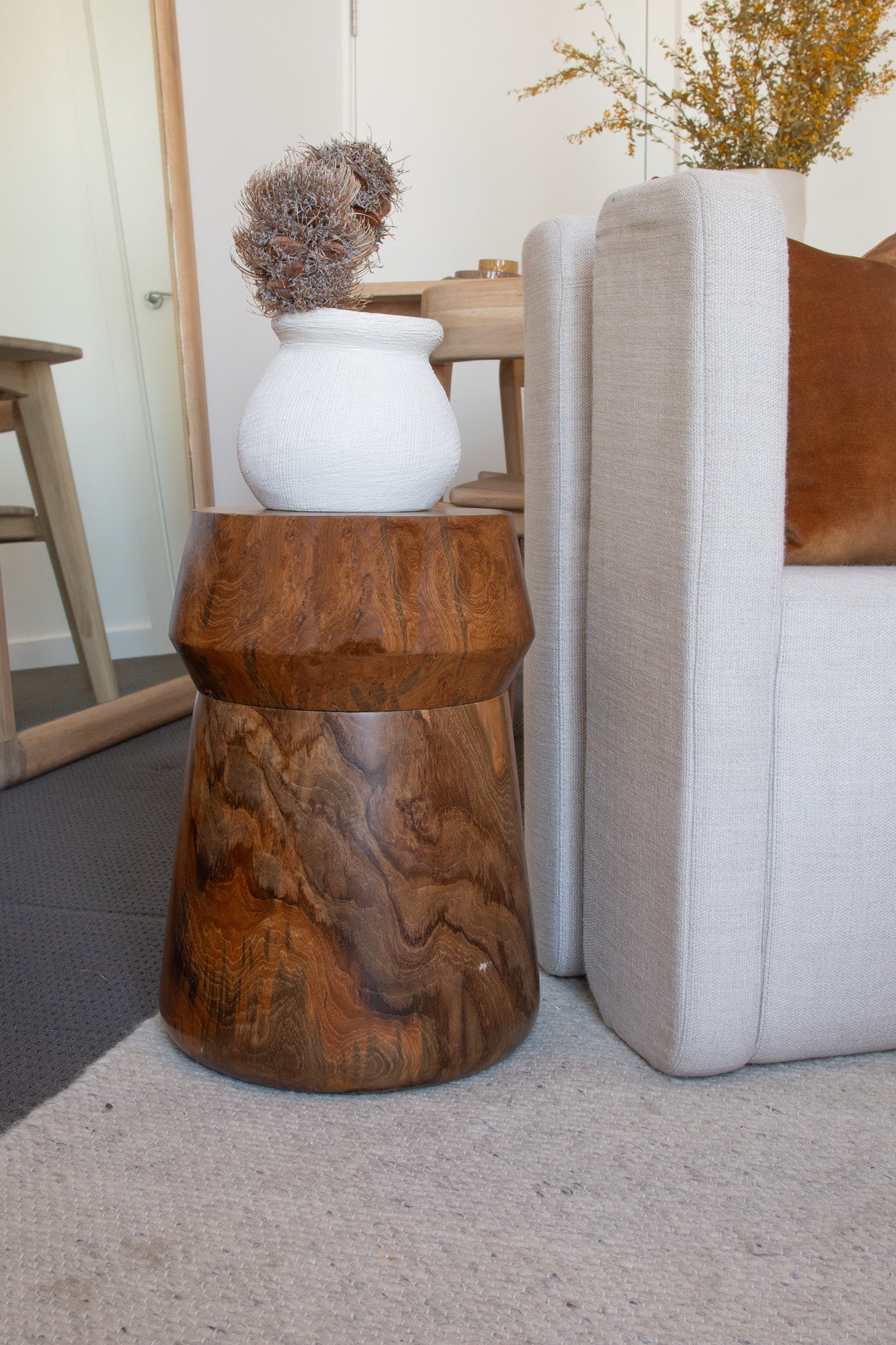 Wooden side table with white vase and dried flowers.