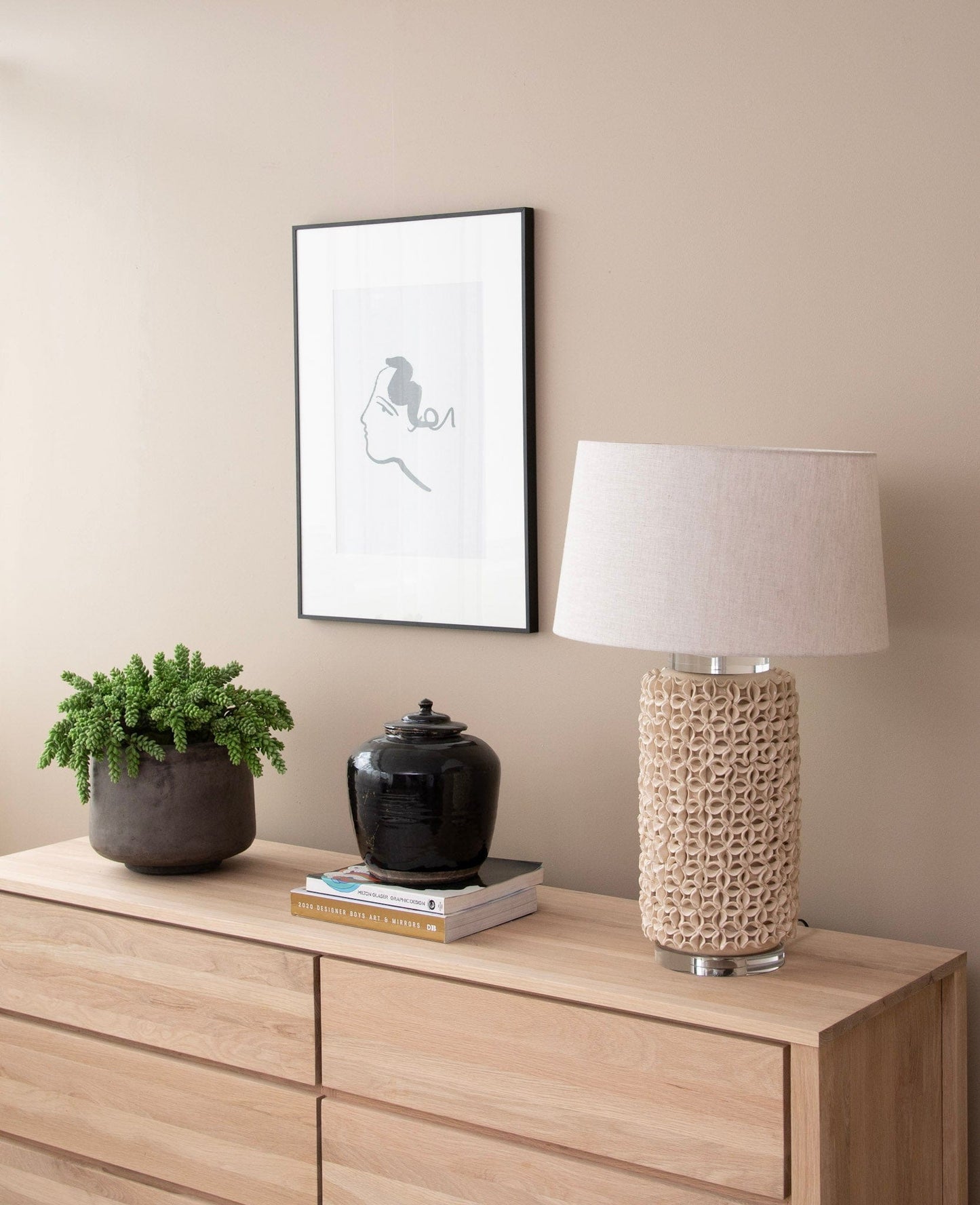 Interior decor with lamp, art, and plant on dresser