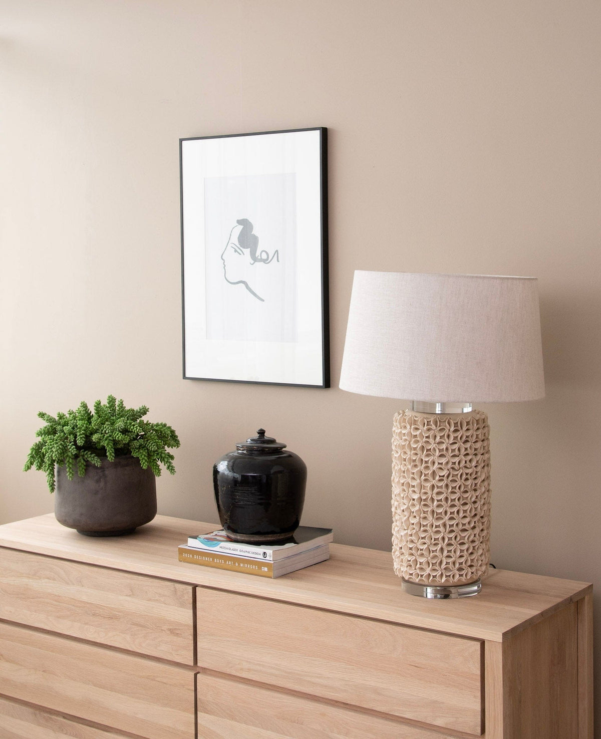 Interior decor with lamp, art, and plant on dresser