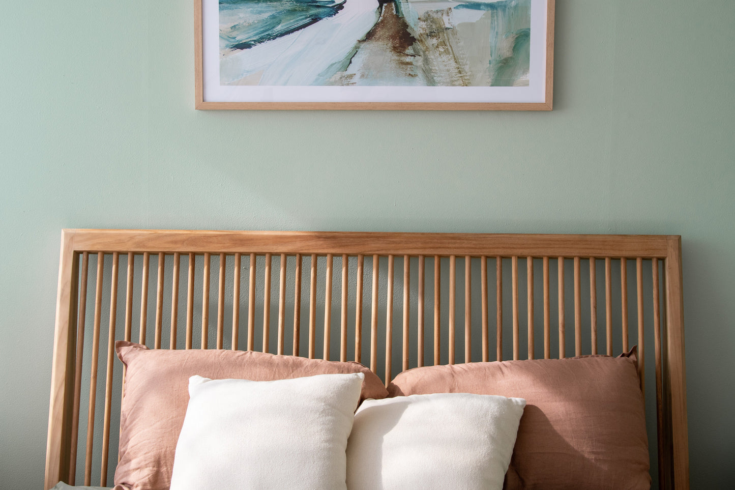 Bedroom with wood headboard and artwork.