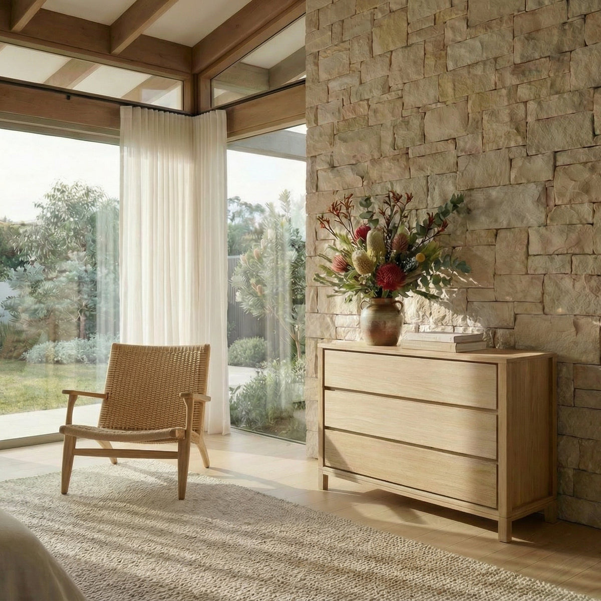Modern bedroom with wooden dresser, chair, and stone wall.