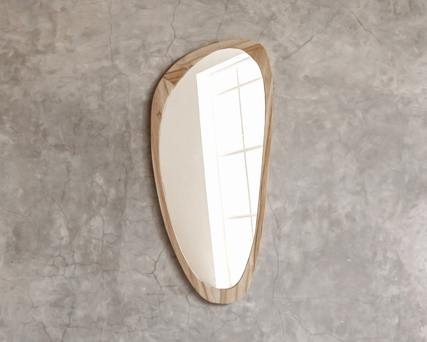 Asymmetrical wood-framed mirror on concrete wall