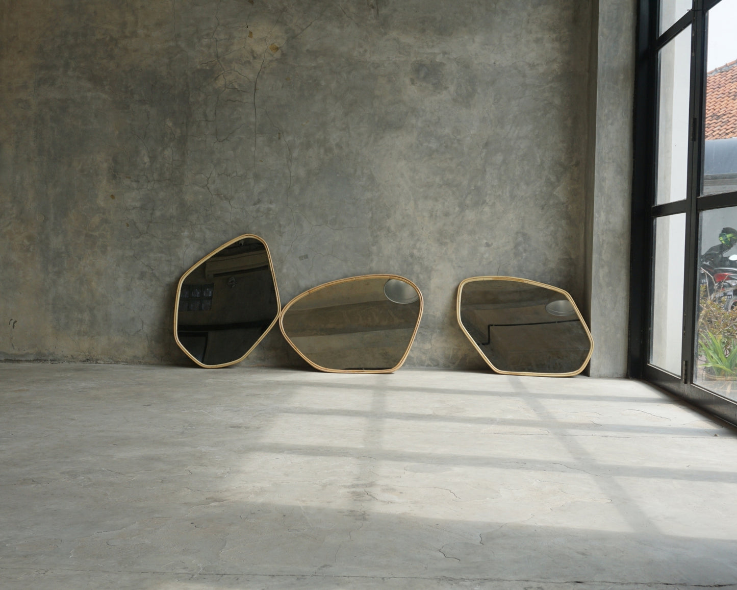 Three abstract mirrors against a concrete wall.