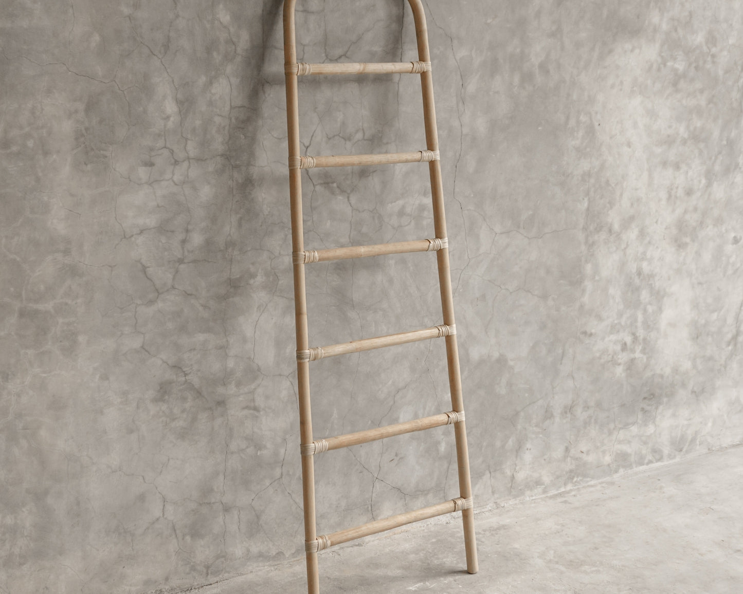 Decorative bamboo ladder leaning against a concrete wall (ELE127_1)