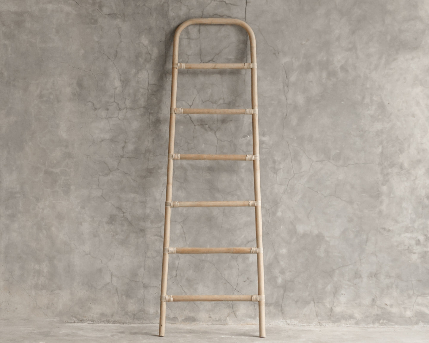 Wooden decorative ladder against a concrete wall.