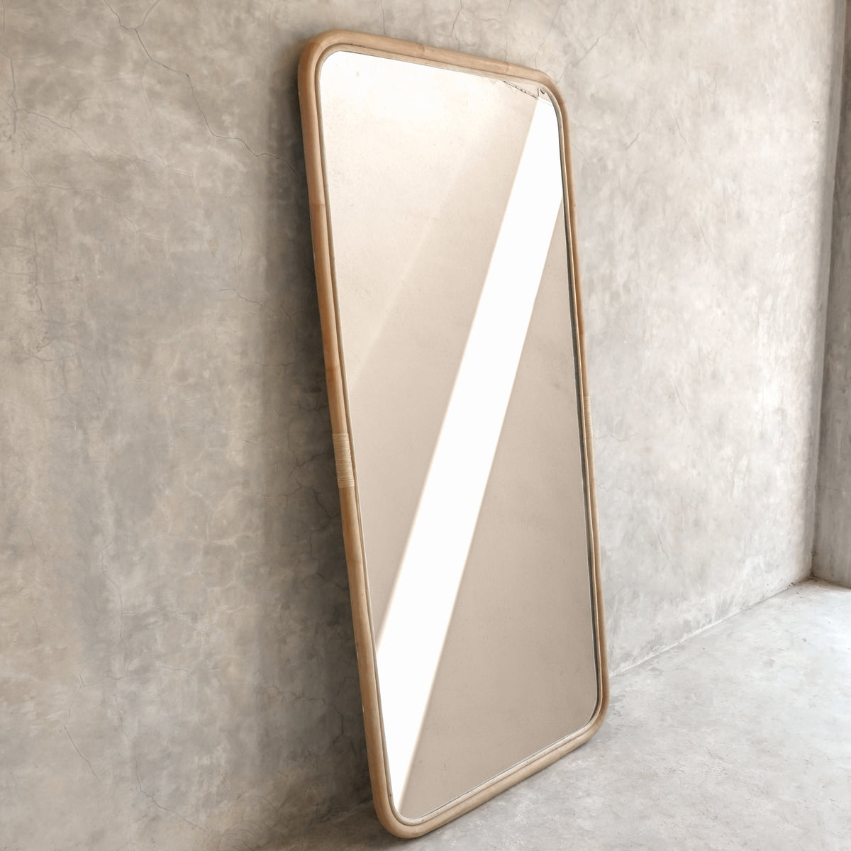 Modern rectangular mirror leaning against concrete wall