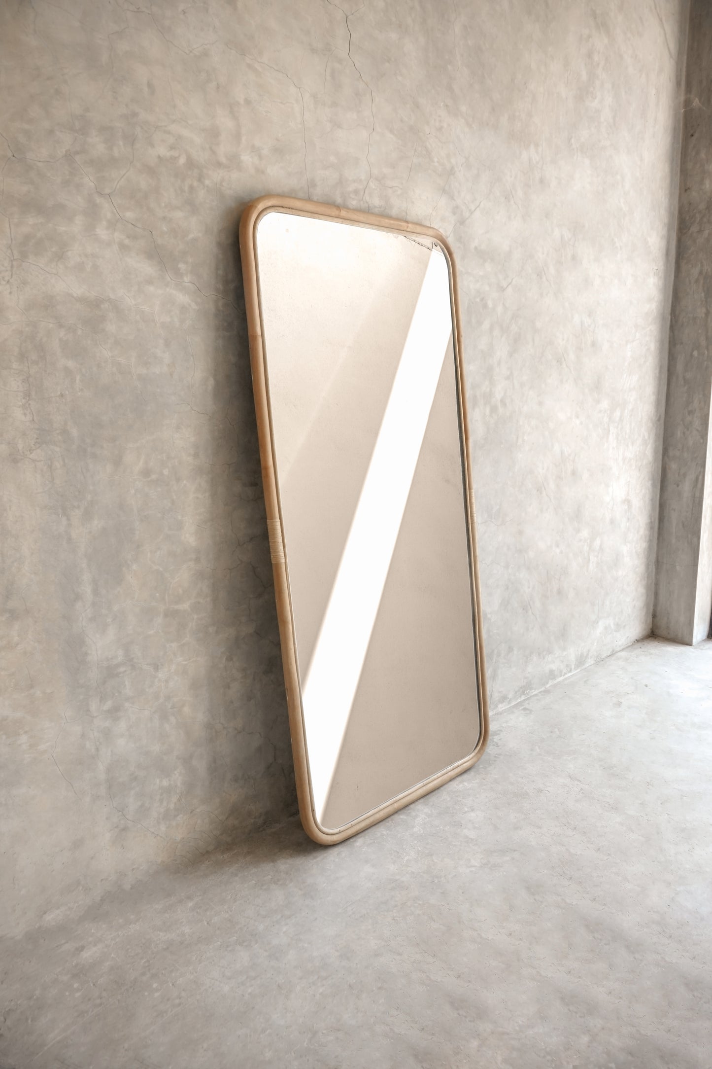 Modern rectangular mirror leaning against concrete wall