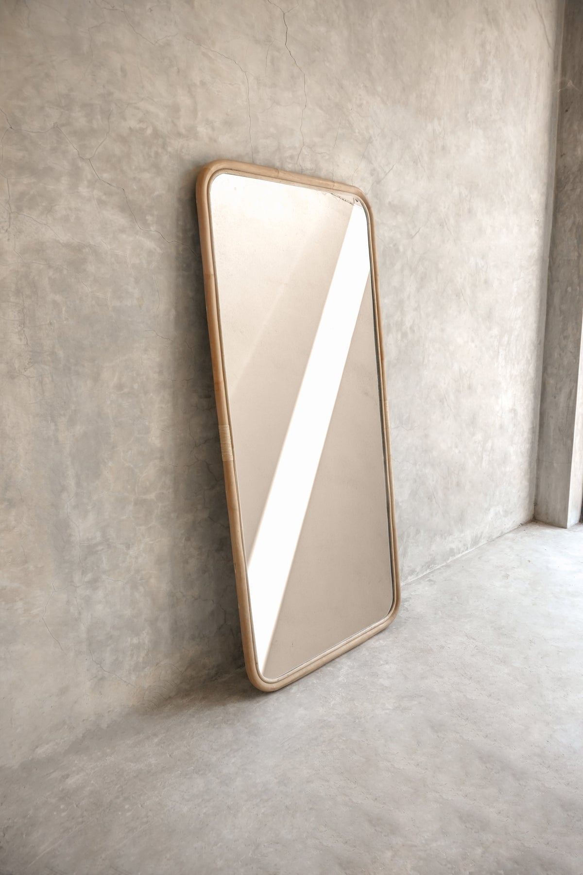 Modern rectangular mirror leaning against concrete wall