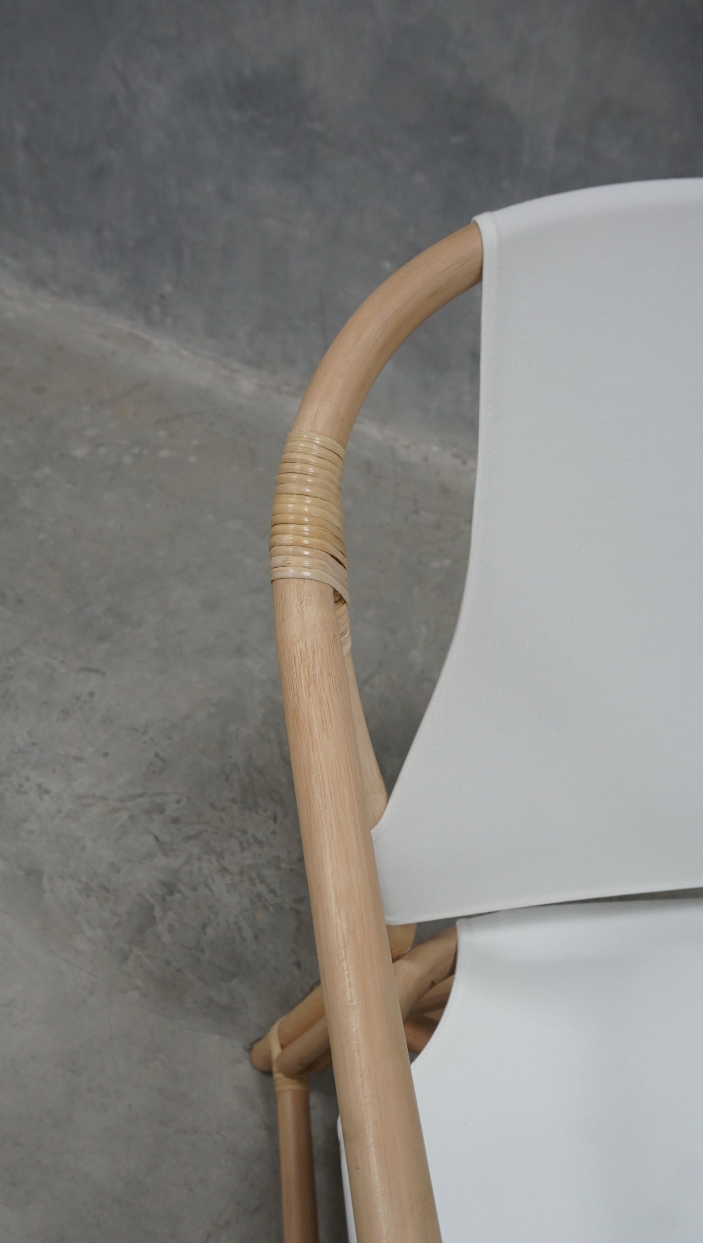 Close-up of white chair back with wood and woven details.