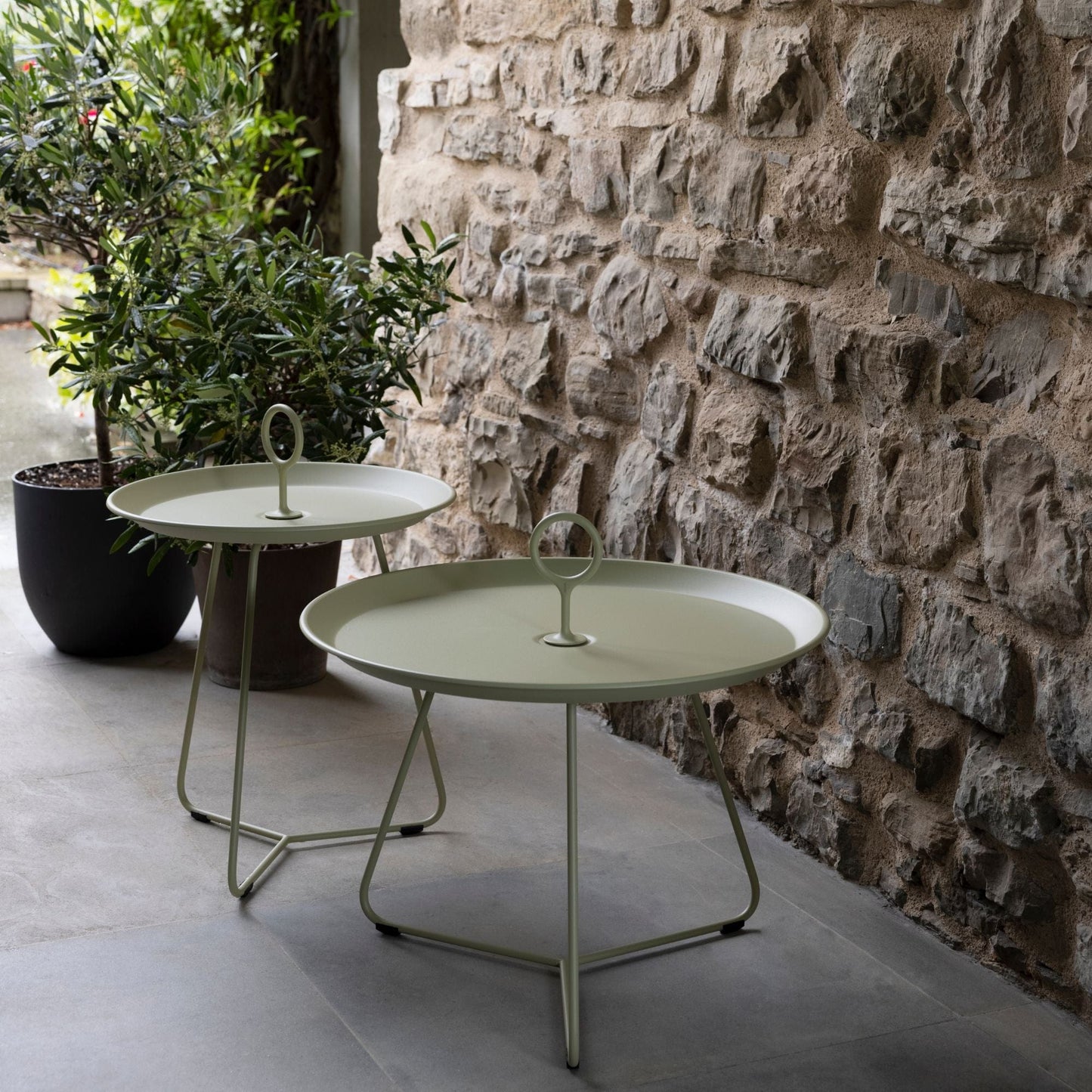Pistachio eyelet tray tables on patio with stone wall