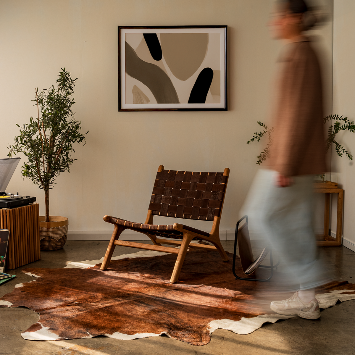 Person walking in a room with a vinyl record player, armchair, and abstract art on the wall.