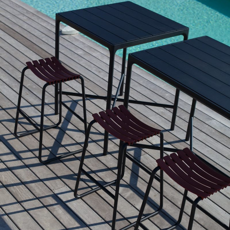 Outdoor bar set with black tables and burgundy stools.
