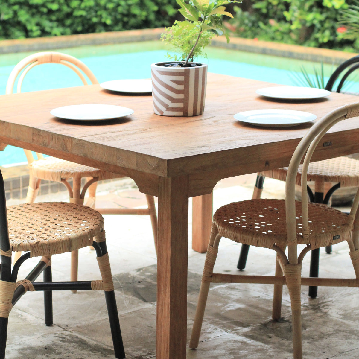 Wooden table set for four with chairs and plant.