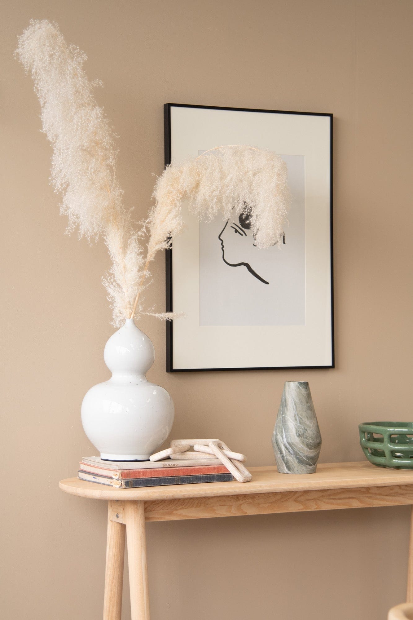 Decorative vase & art print on a wooden table.