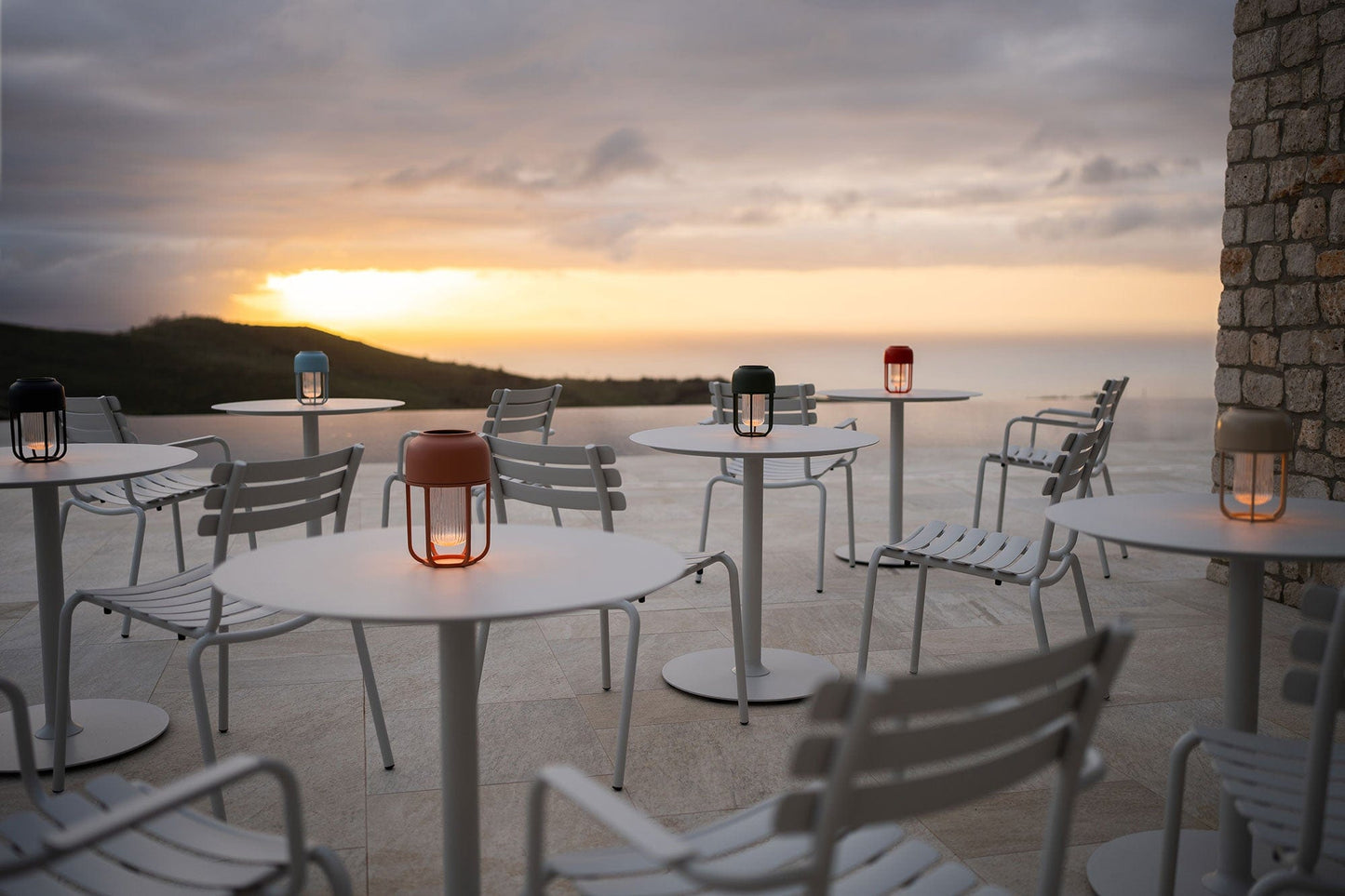 Outdoor dining scene with Houe Pico tables and lanterns at sunset.