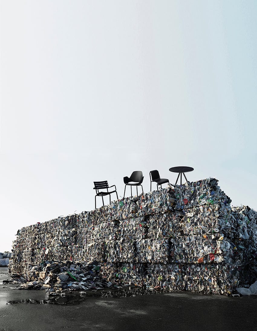 Furniture atop a trash pile against a high sky.