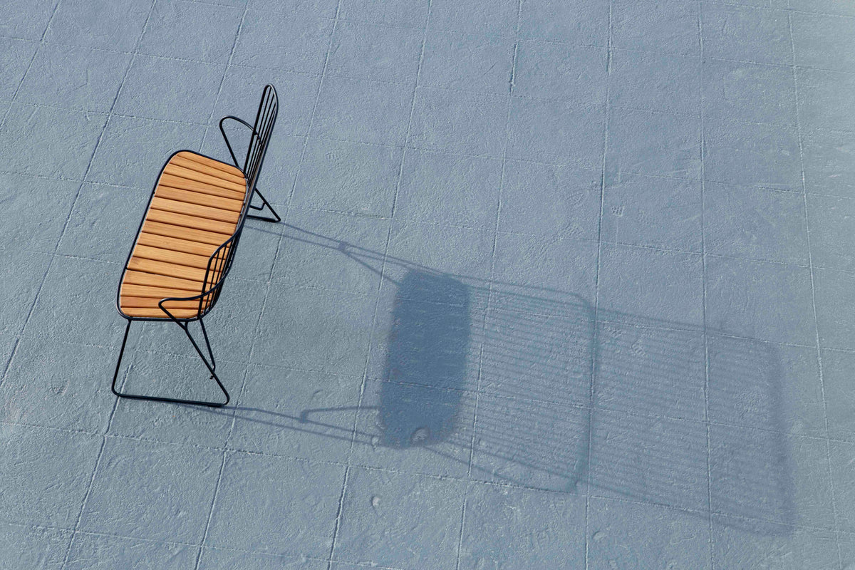 Black HOUE bench with wooden seat casting shadow