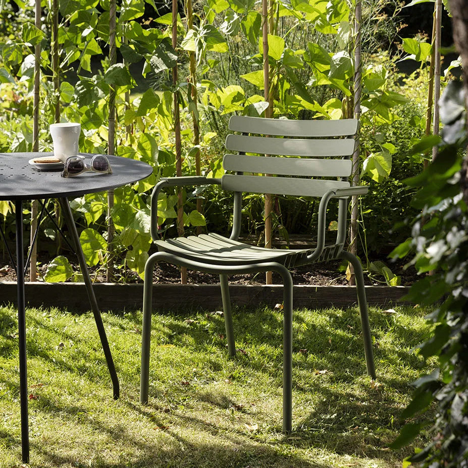 Garden scene with a chair, table, and cup under a tree