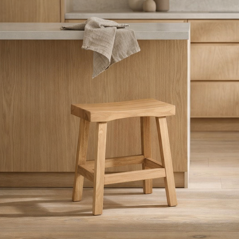 Wooden stool in a kitchen setting with light wood cabinets and a towel.