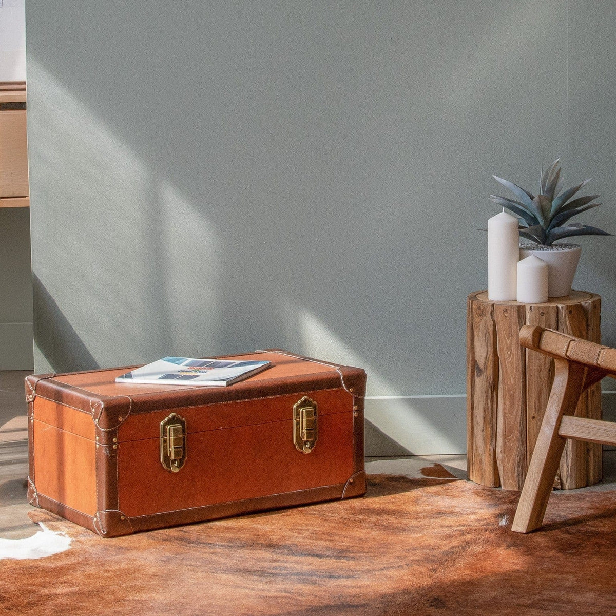 Brown trunk, plant, candles on wood side table