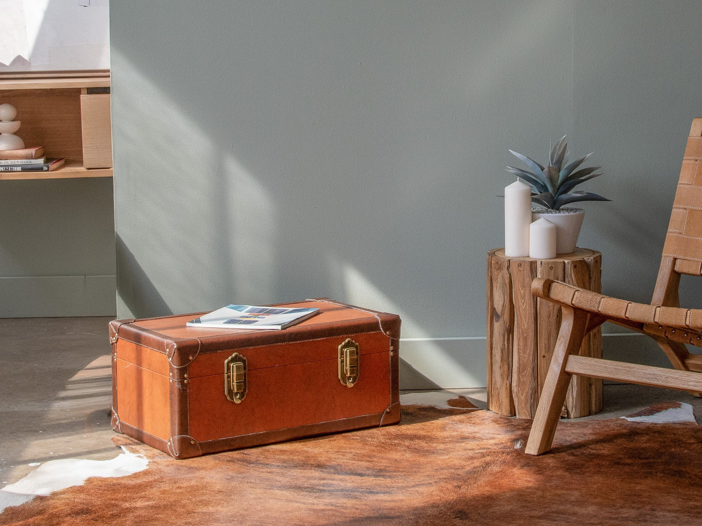 Brown trunk, plant, candles on wood side table