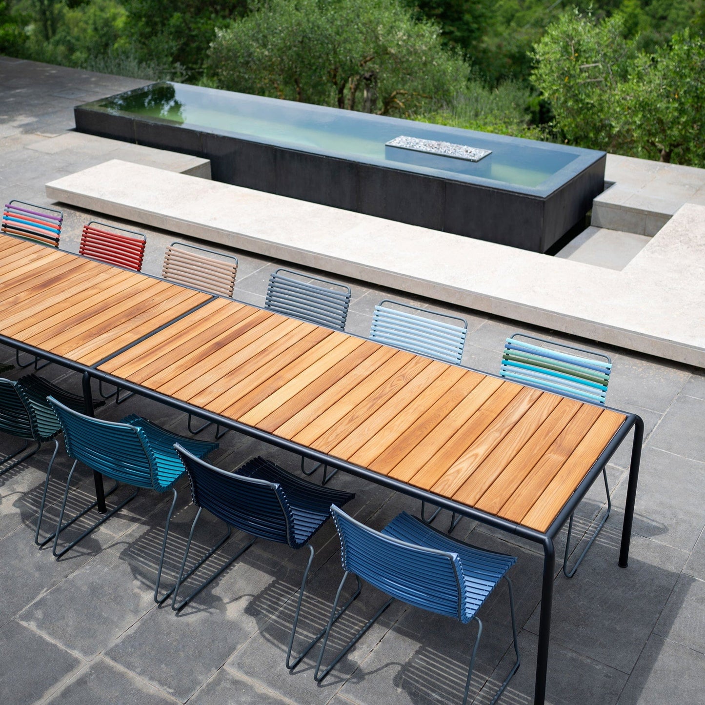 Outdoor dining table with no-arm chairs near pool.