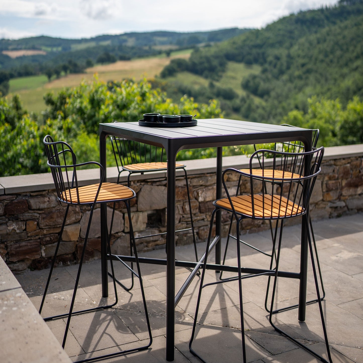 Paon bar stool set with table on patio overlooking scenic view.