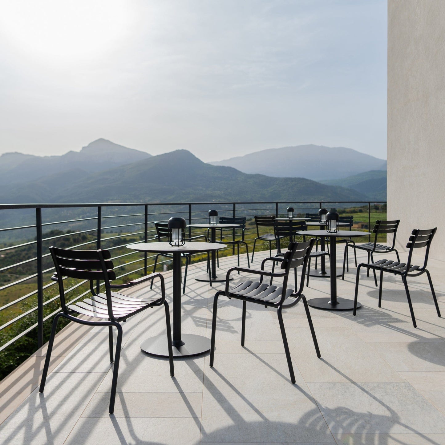 Black ALUA outdoor furniture on a patio with mountain views
