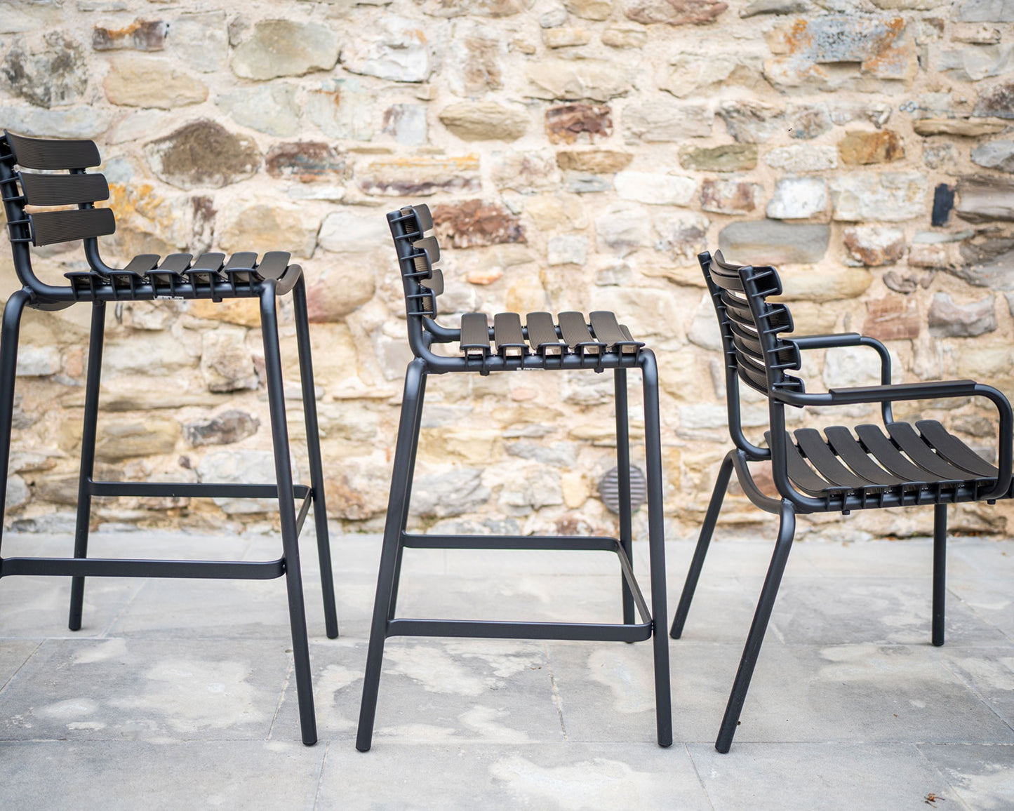 Black reclips dining chairs against stone wall