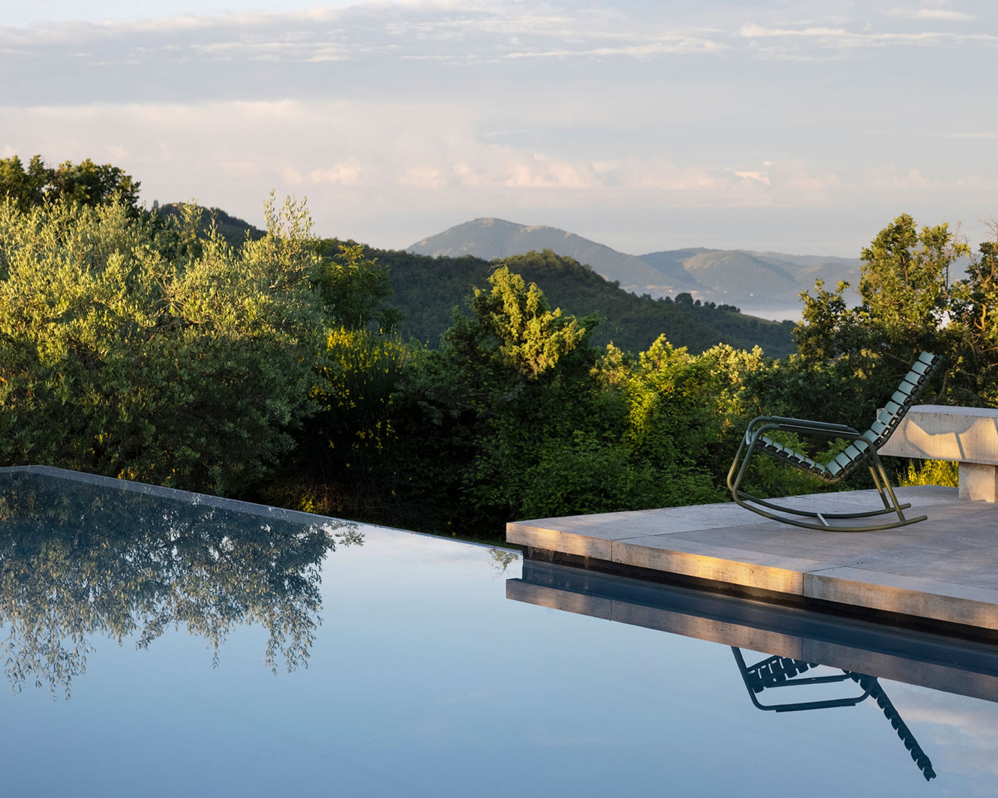 Olive green rocking chair by pool overlooking mountains