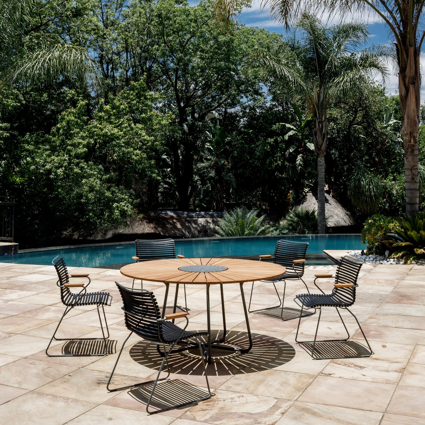 Patio furniture set around a round table near a pool.