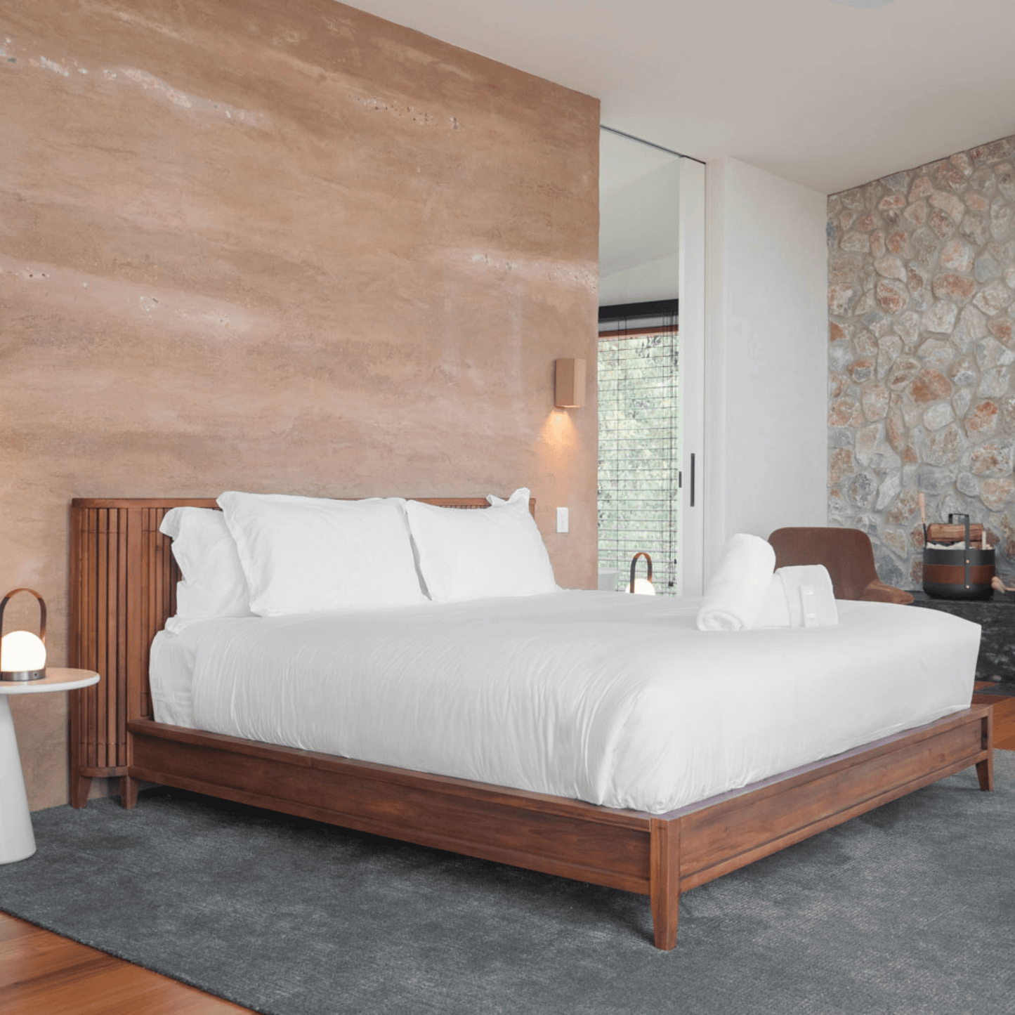 Bedroom with bed, white linens, and stone wall.